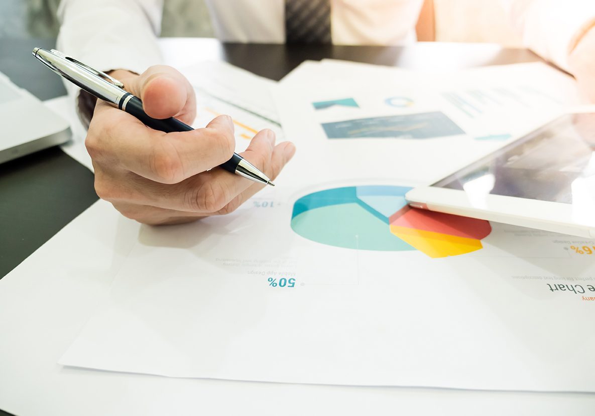 Close up of Businessman analyzing investment charts and using ta Close up of Businessman analyzing investment charts and using tablet on the desk.